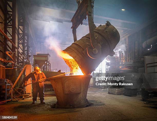 steel worker cleaning large ladle in an industrial foundry - energieerzeugung stock-fotos und bilder