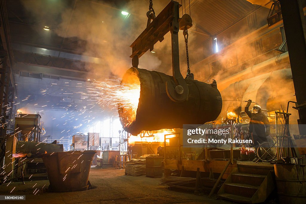 Steel worker cleaning large ladle in an industrial foundry