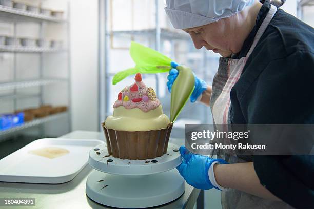 chocolatier icing large cup cake in chocolate factory with piping bag - candy factory 個照片及圖片檔