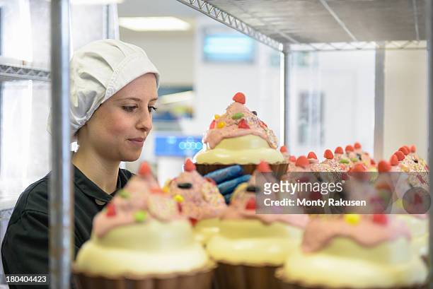 chocolatier arranging large chocolate cup cake on shelf in chocolate factory - bakning business bildbanksfoton och bilder
