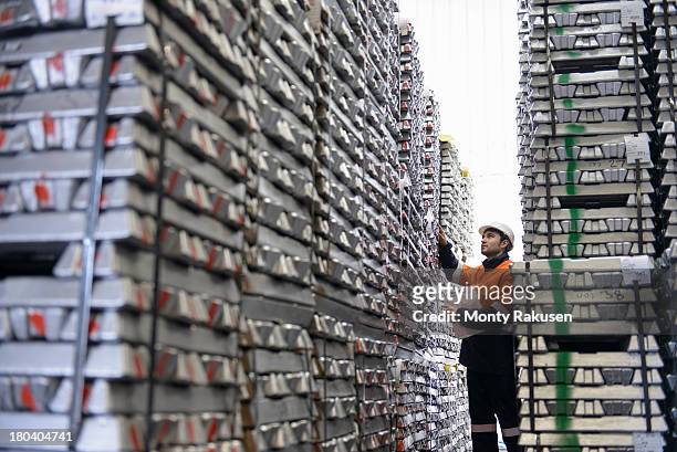 warehouse worker checking stacked aluminum ingots - aluminium ingots stockfoto's en -beelden