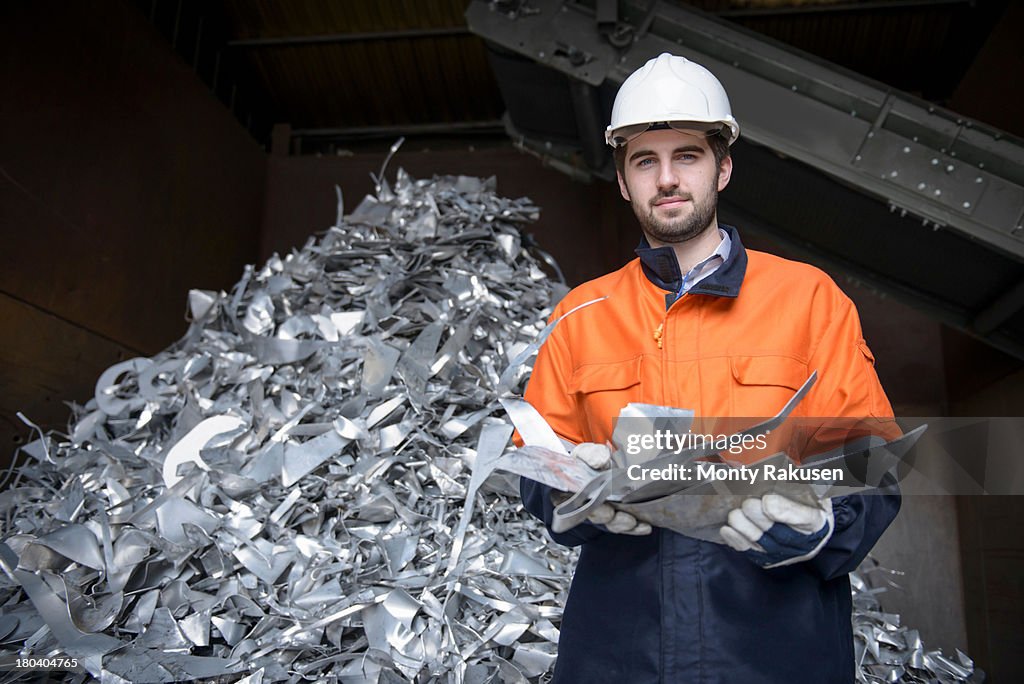Worker inspecting aluminium scrap in aluminium recycling plant, portrait