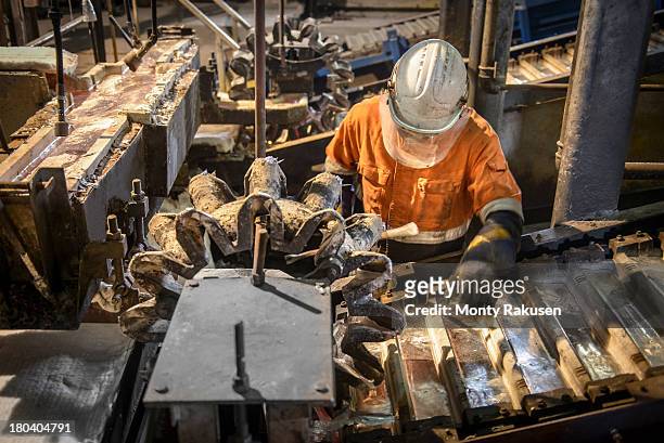 worker operating ingot casting machine in aluminium foundry - aluminium ingots stockfoto's en -beelden