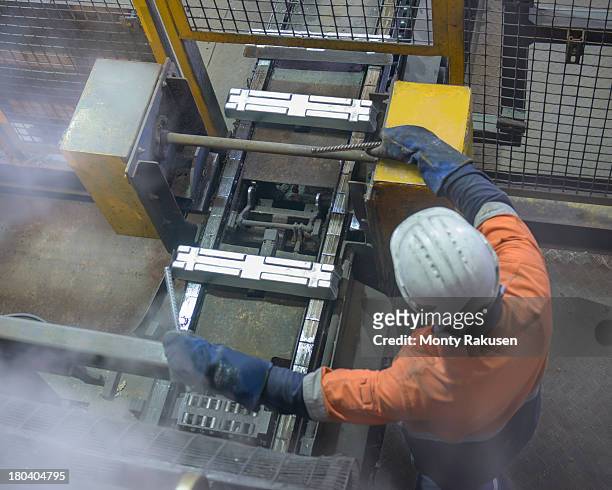 overhead view of worker with hot ingots in aluminium foundry - aluminium ingots stockfoto's en -beelden