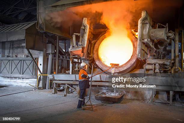 worker taking sample from furnace in aluminium recycling plant - aluminio imagens e fotografias de stock