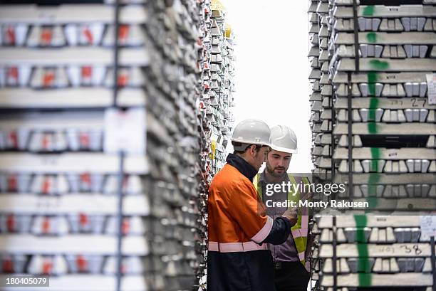 workers inspecting stacks of aluminium ingots in warehouse - warwickshire stock photos et images de collection