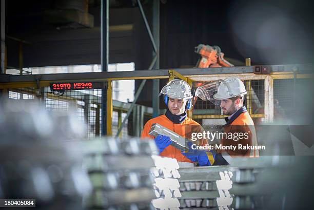 workers in protective workwear inspecting aluminium ingot in foundry - alluminium photos et images de collection