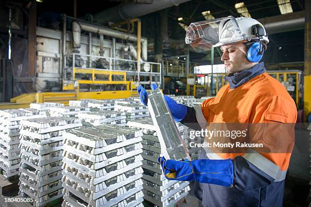 worker in protective workwear inspecting aluminium ingot in foundry - pewter stock pictures, royalty-free photos & images