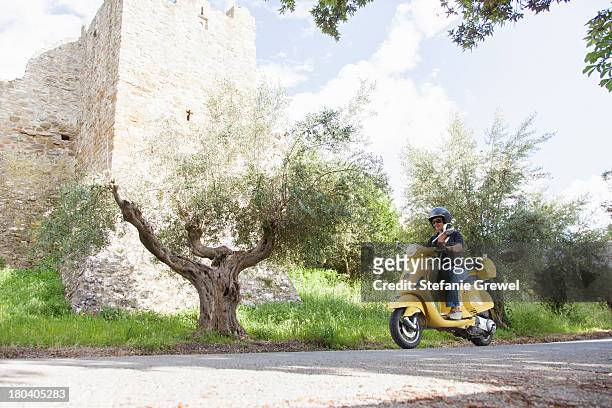woman on scooter riding around corner - riding vespa stock pictures, royalty-free photos & images