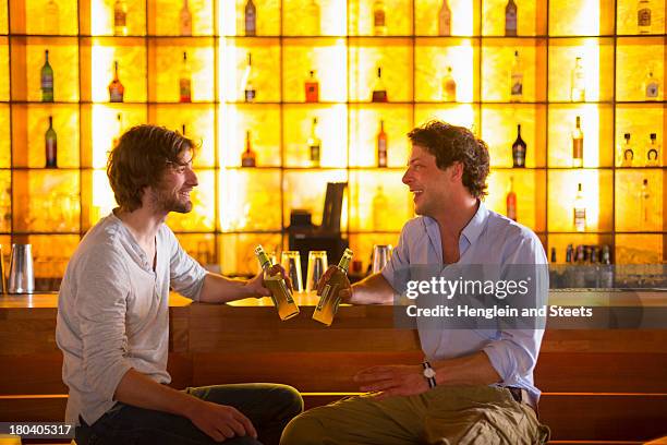 two men sitting at bar with bottles of beer - bar man t shirt ストックフォトと画像