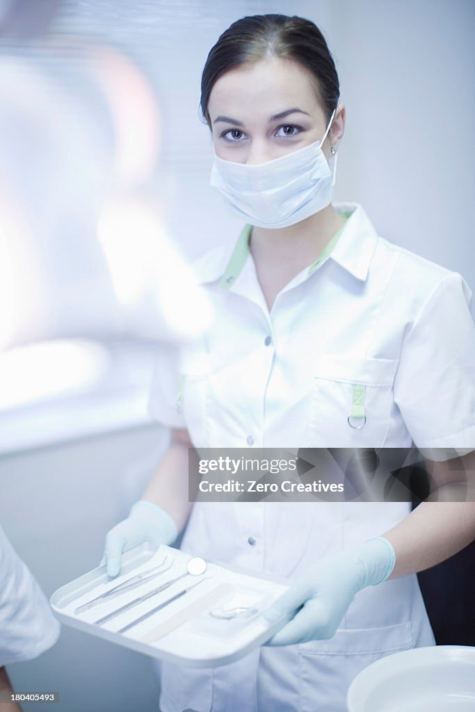 Portrait of female dental nurse holding surgical tray