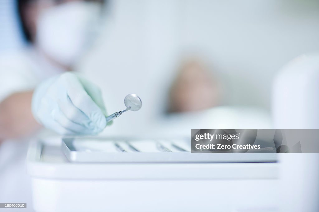 Close up of hand holding dentist mirror