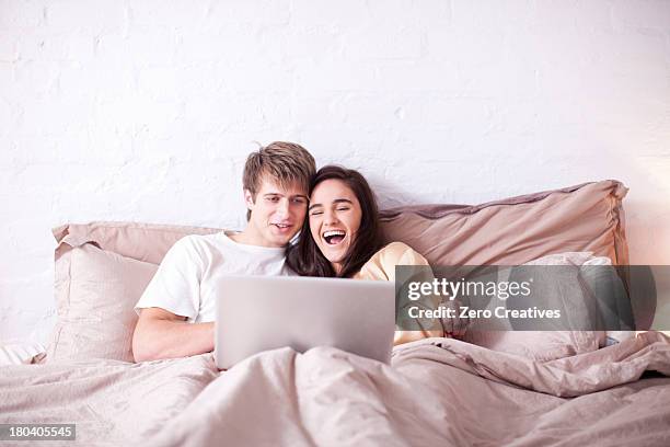 young couple watching laptop in bed - bed on white stock pictures, royalty-free photos & images