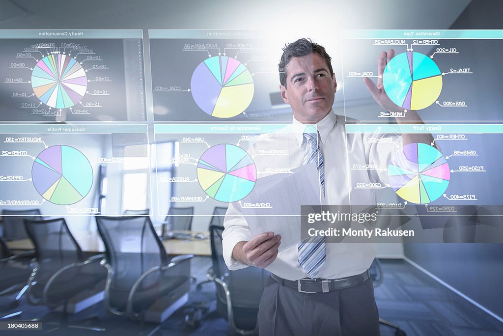 Businessman looking at pie charts on interactive screen