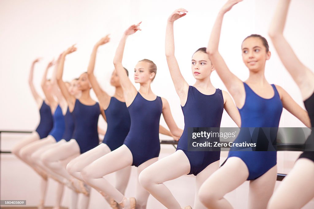 Row of teenage ballerinas with arms outstretched