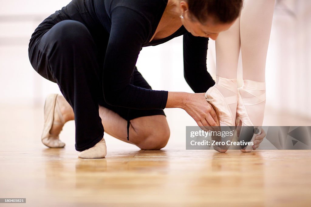 Teacher adjusting foot position of ballerina