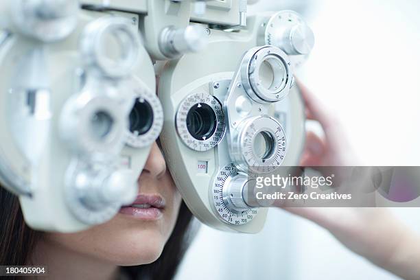 young woman having eye test - eye test equipment stock photos et images de collection