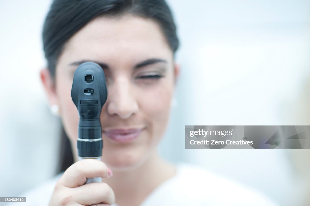 Portrait of optician looking through ophthalmoscope