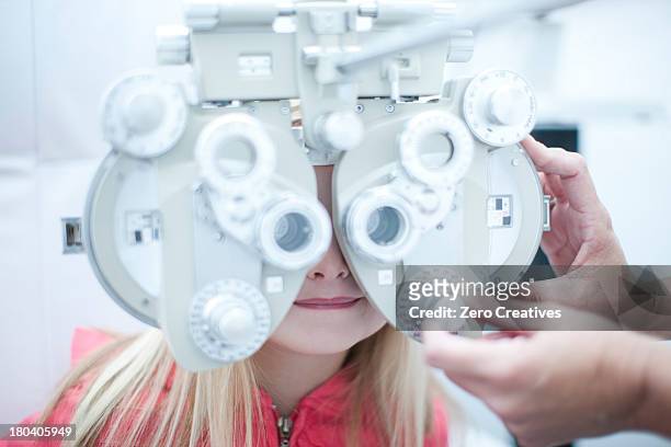optician testing young girl in eye clinic - réfracteur photos et images de collection