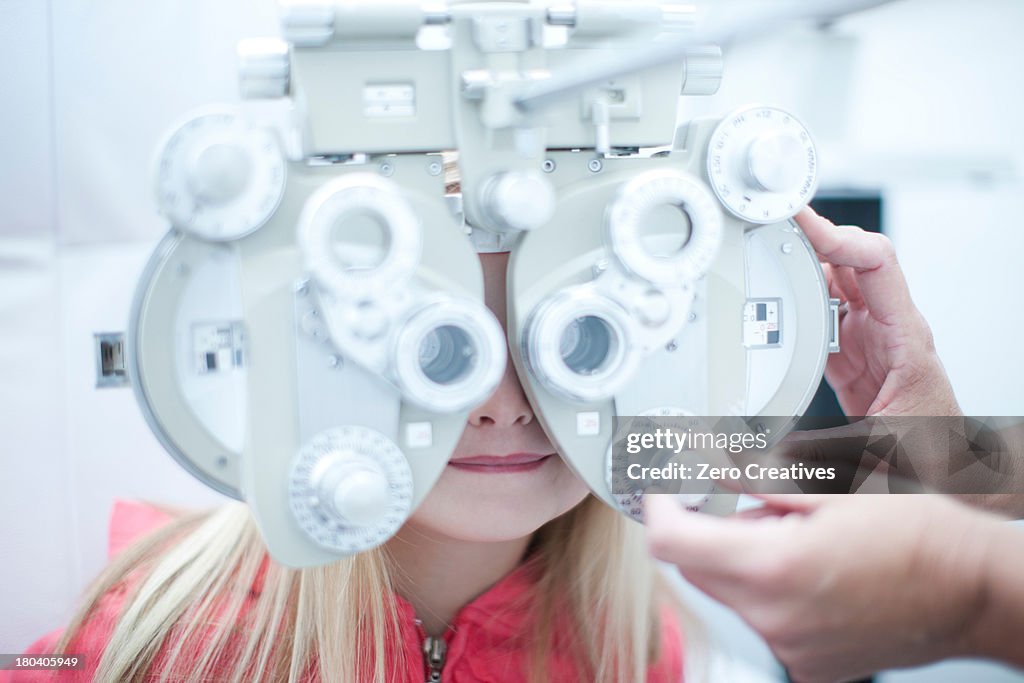 Optician testing young girl in eye clinic