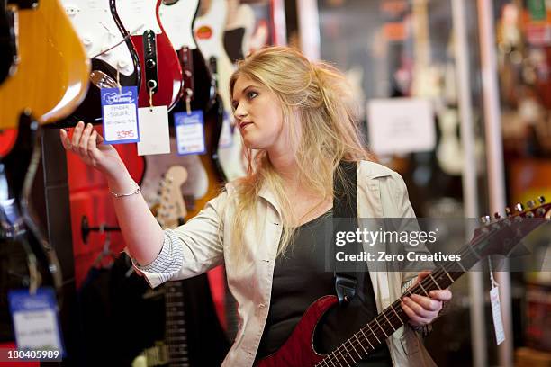 young women looking at guitars in music store - guitar shop stock pictures, royalty-free photos & images