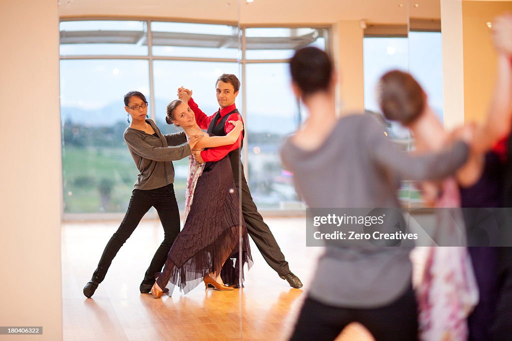 Dance teacher and ballroom dancers looking in mirror