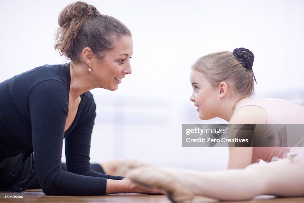 Teacher and young ballerina practicing floor stretch