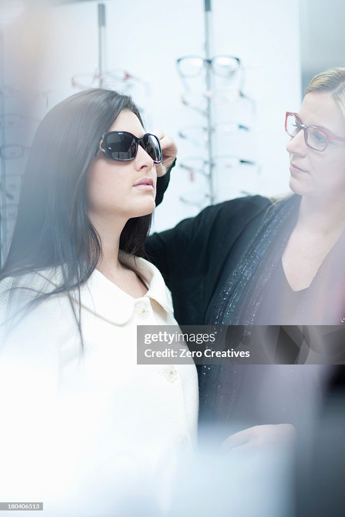 Woman trying on sunglasses in opticians shop