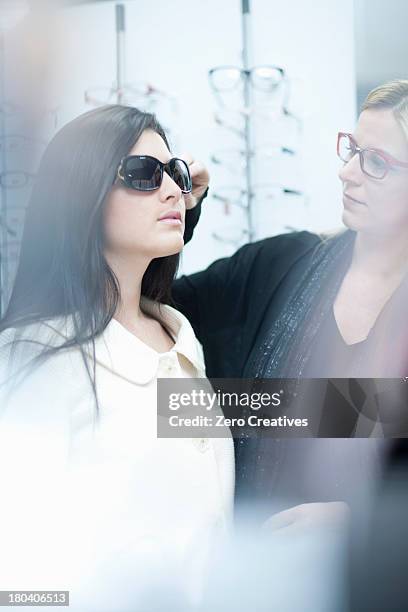Woman Trying On Sunglasses In Opticians Shop, Foto de stock