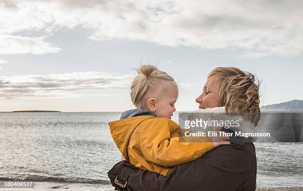 grandmother and toddler hugging at coast - reykjavik women stockfoto's en -beelden