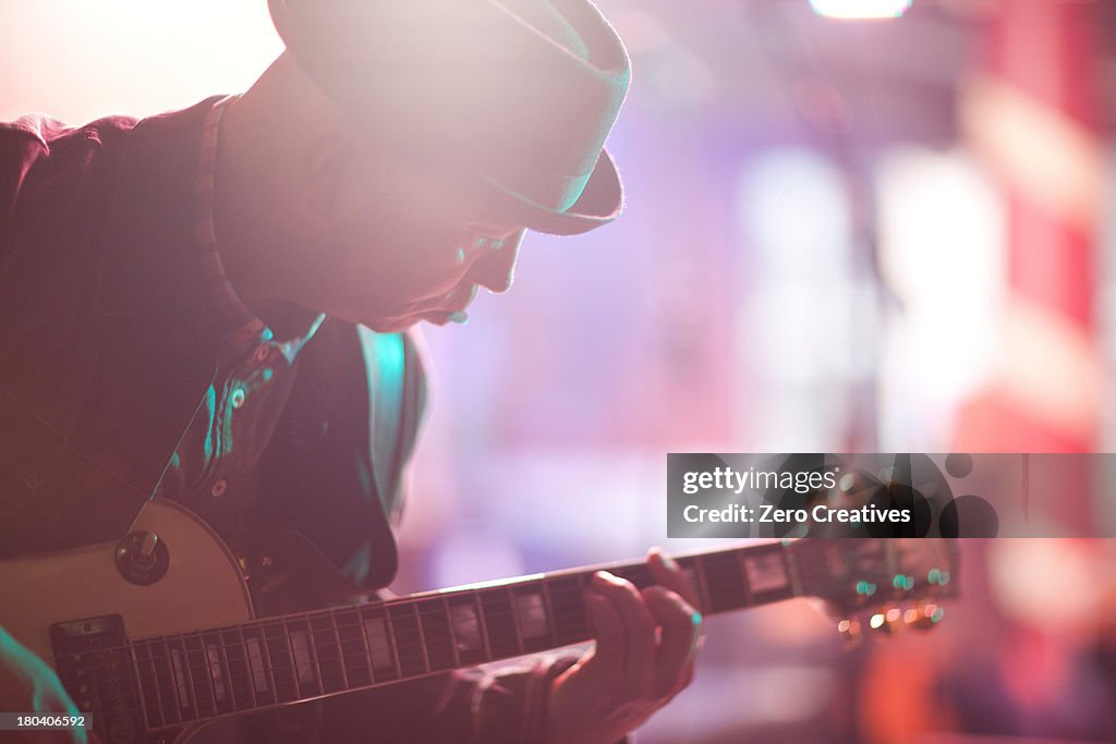 Close up mature man playing guitar on stage