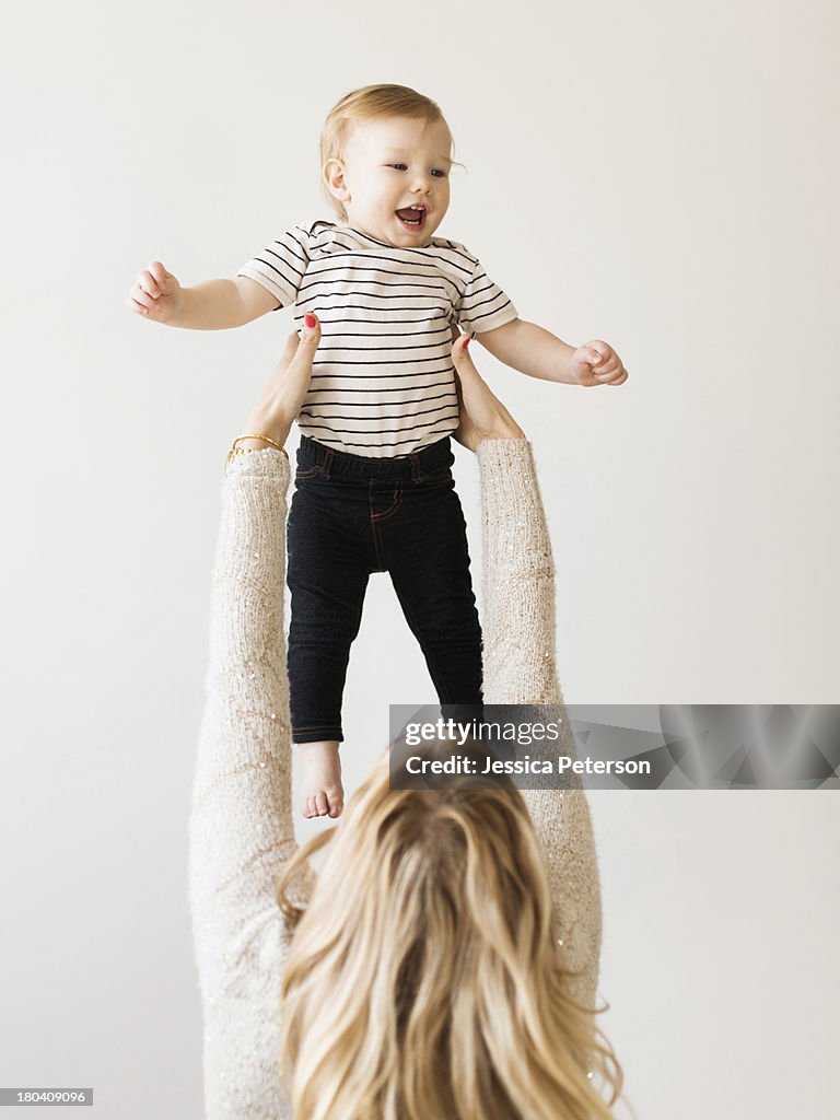 Mother holding up her daughter (12-17 months)