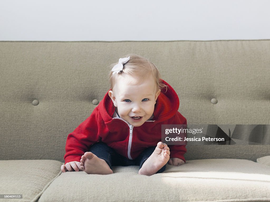 Portrait of baby girl (12-17 months) sitting on sofa