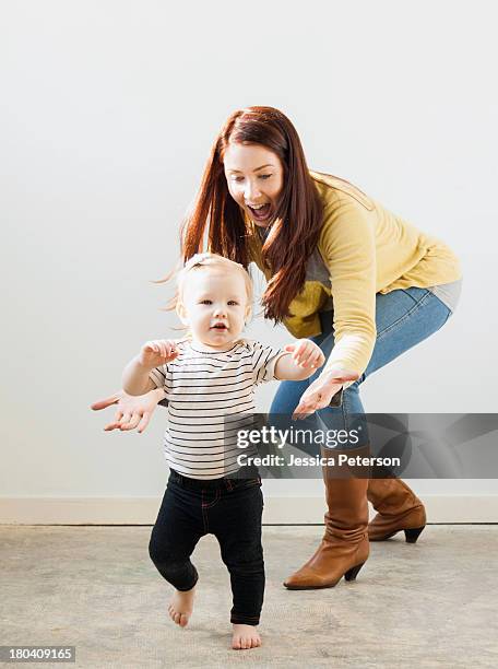 baby girl (12-17 months) walking while mother assisting her - primeiros passos imagens e fotografias de stock