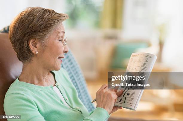 usa, new jersey, jersey city, senior woman doing crossword puzzle - senior puzzle stock pictures, royalty-free photos & images