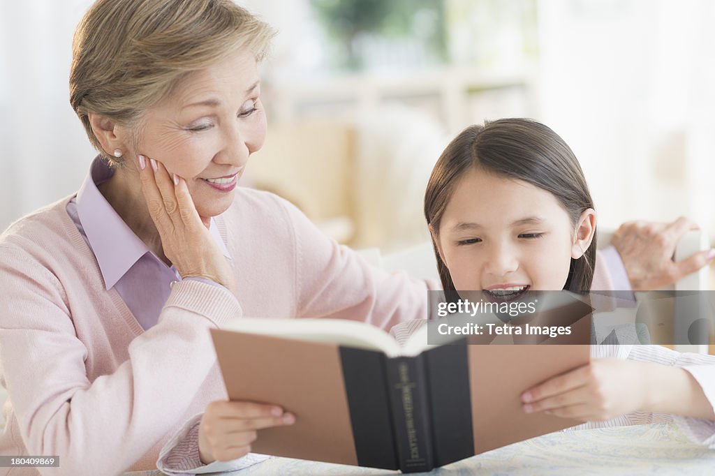 USA, New Jersey, Jersey City, Granddaughter (8-9) and grandmother reading book