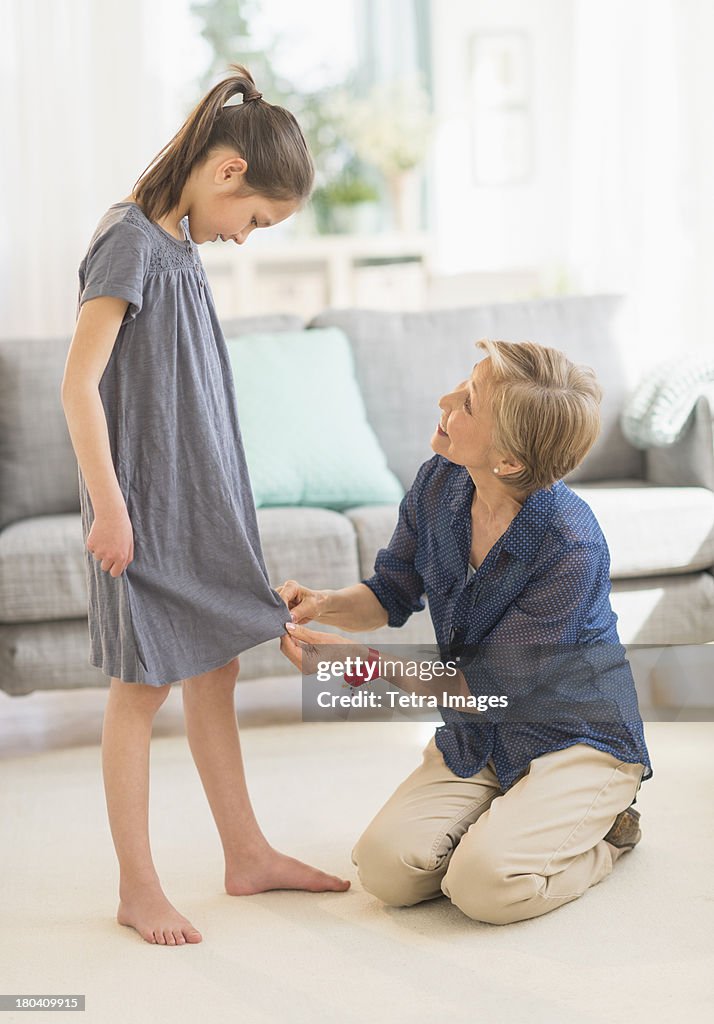 USA, New Jersey, Jersey City, Grandmother attaching sewing pins to granddaughter's (8-9) dress