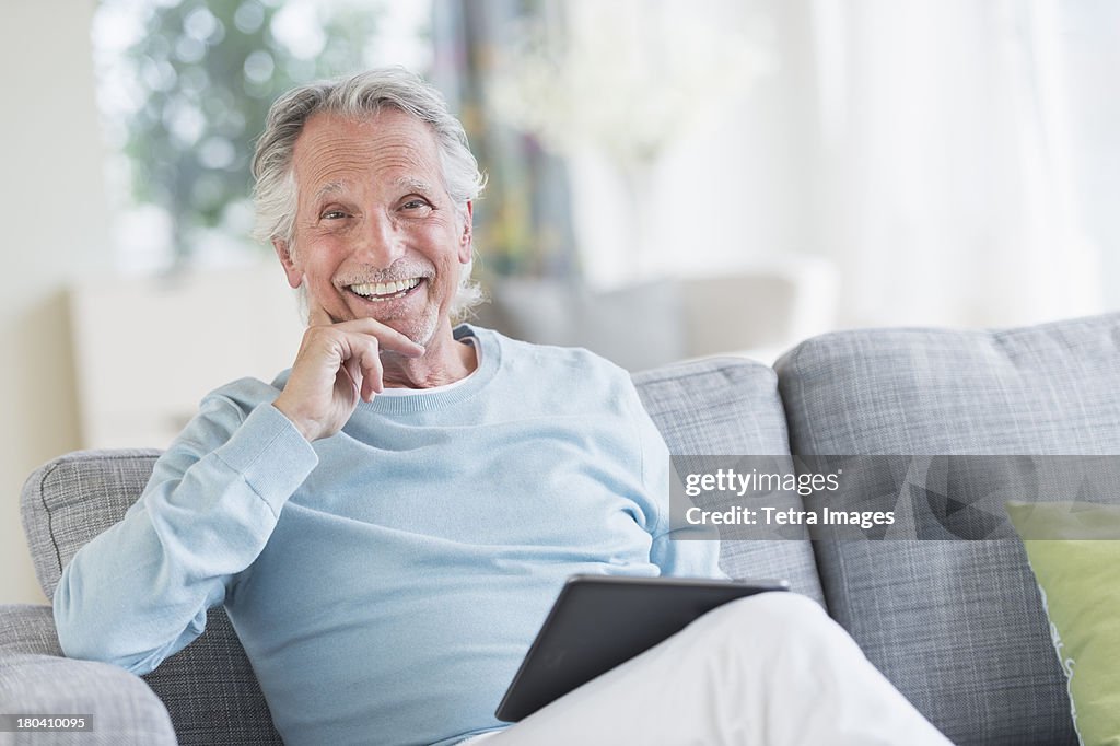 USA, New Jersey, Jersey City, Senior man sitting on sofa with digital tablet