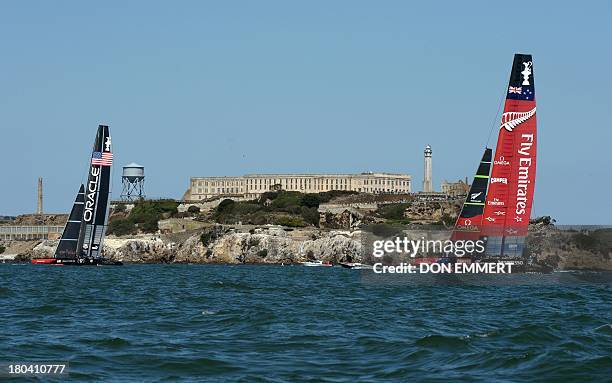 Oracle Team USA races against Emirates Team New Zealand past Alcatraz Island while competing in the first race of the day during the 34th America's...