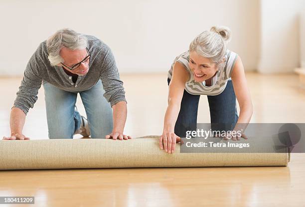 usa, new jersey, jersey city, man and woman rolling carpet - carpet roll stock-fotos und bilder