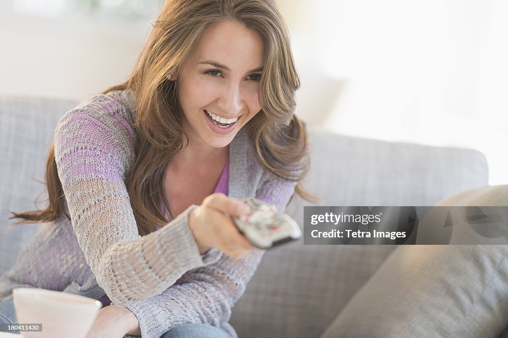 USA, New Jersey, Jersey City, Young woman watching tv on sofa