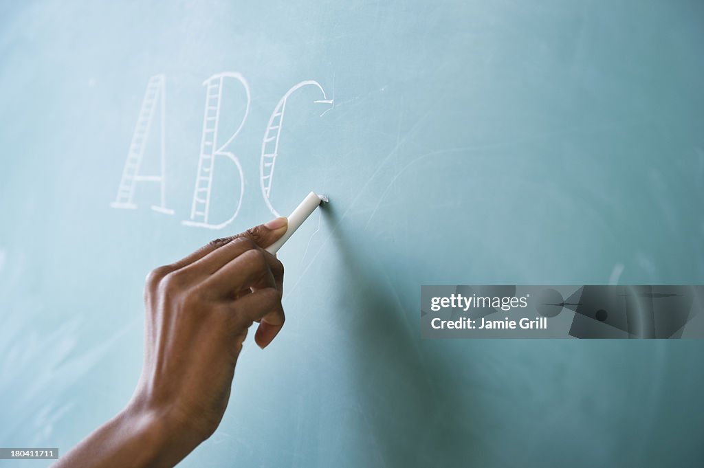 USA, New Jersey, Jersey City, Close up of woman's hand writing alphabet on blackboard