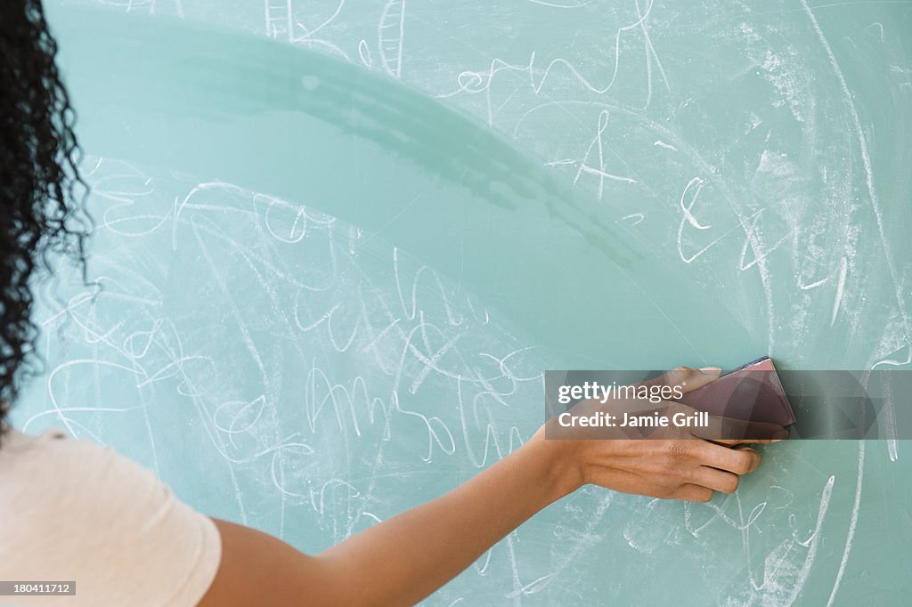 USA, New Jersey, Jersey City, Rear view of woman erasing blackboard
