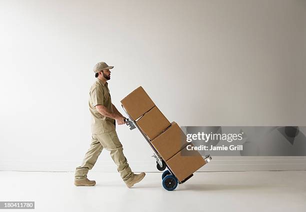 usa, new jersey, jersey city, delivery man walking with push cart - rollwagen stock-fotos und bilder