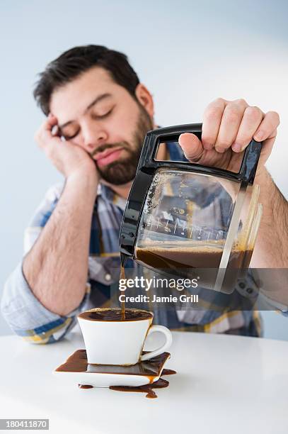usa, new jersey, jersey city, tired, sleepy man spilling coffee on table - ignorance foto e immagini stock