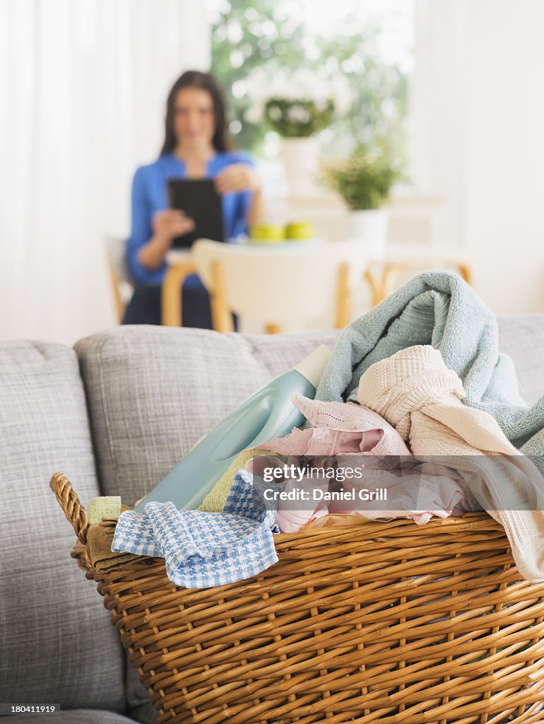USA, New Jersey, Jersey City, Laundry basket on sofa and woman in background