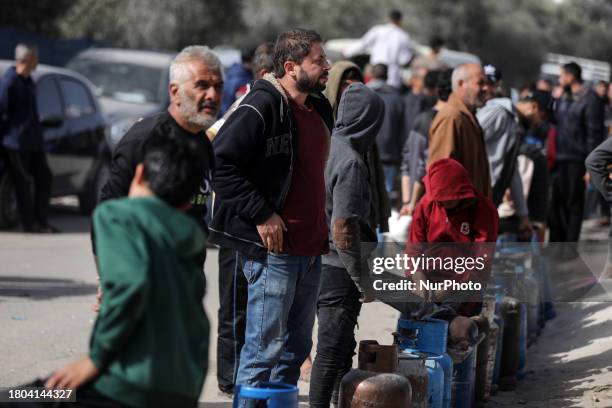 People are waiting with empty canisters to be filled with cooking gas from a tank that has entered the Palestinian enclave via the Rafah crossing...