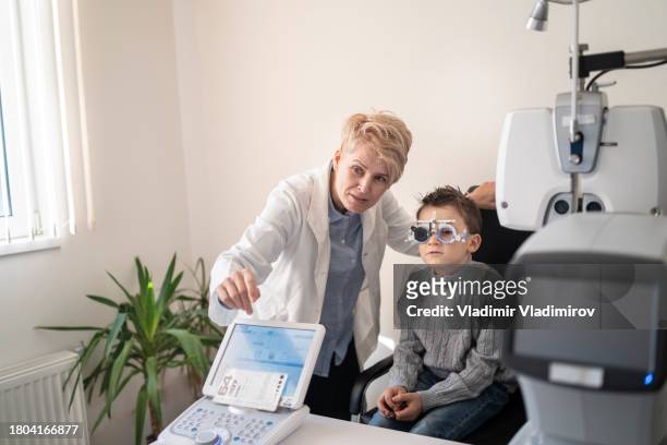 female optometrist performing an eye test on a young boy wearing special ophthalmic glasses - special screening of lemony snickets a series of unfortunate events stockfoto's en -beelden