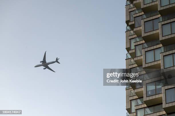 An airplane flies past high rise apartments at Canary Wharf on November 4, 2023 in London, United Kingdom.