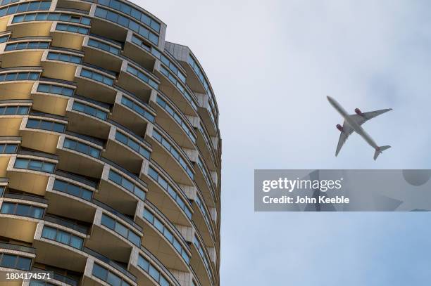 An airplane flies past high rise apartments at Canary Wharf on November 4, 2023 in London, United Kingdom.